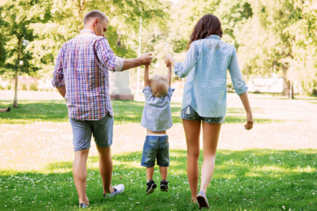 Mother and father holding their son in the air in the summer garden.