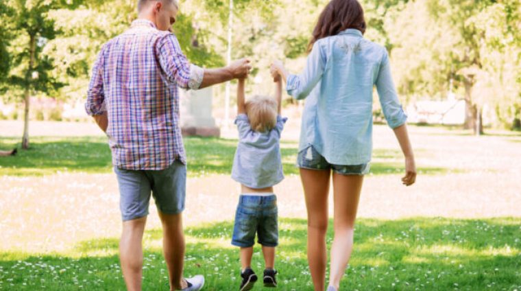 Mother and father holding their son in the air in the summer garden.